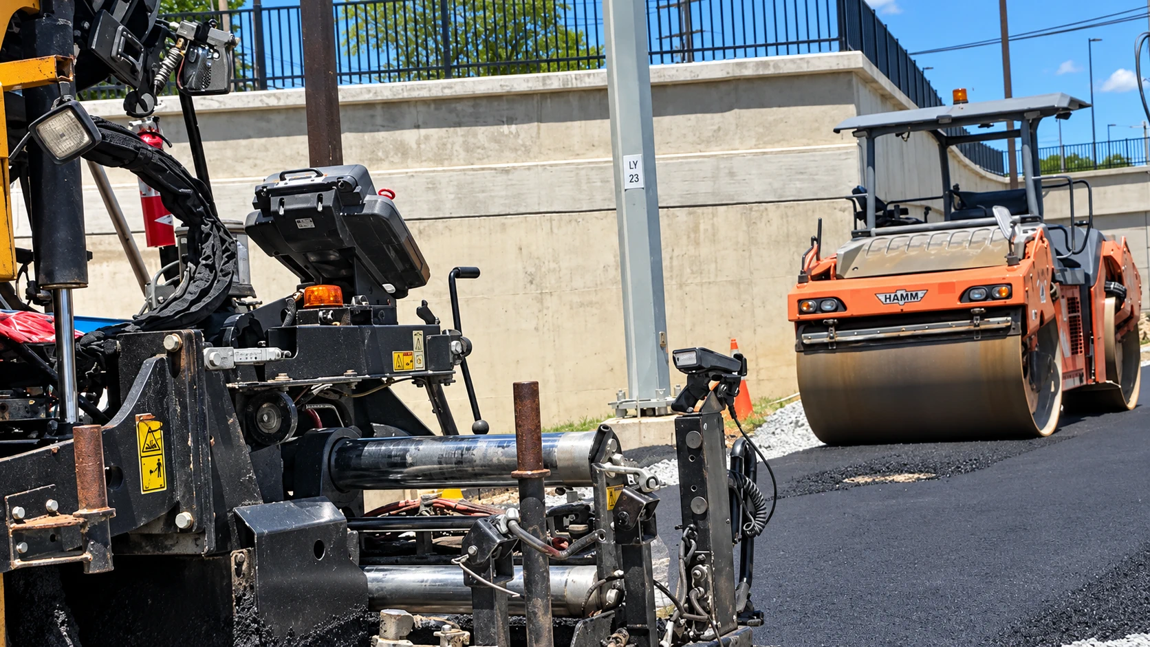 Asphalt paver and roller working together on a Soli Paving project